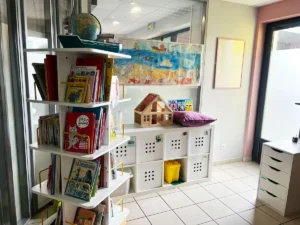 Livres, jeux et maison de poupée dans un espace pédagogique du DAPAS
