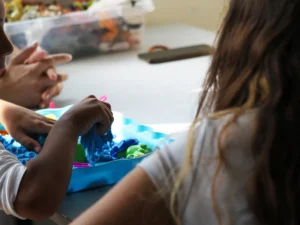 Enfant participant à une activité sensorielle autour d’un bac de manipulation au DAPE