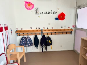 Porte-manteaux et sacs d’enfants dans l’espace d’accueil du DAPE